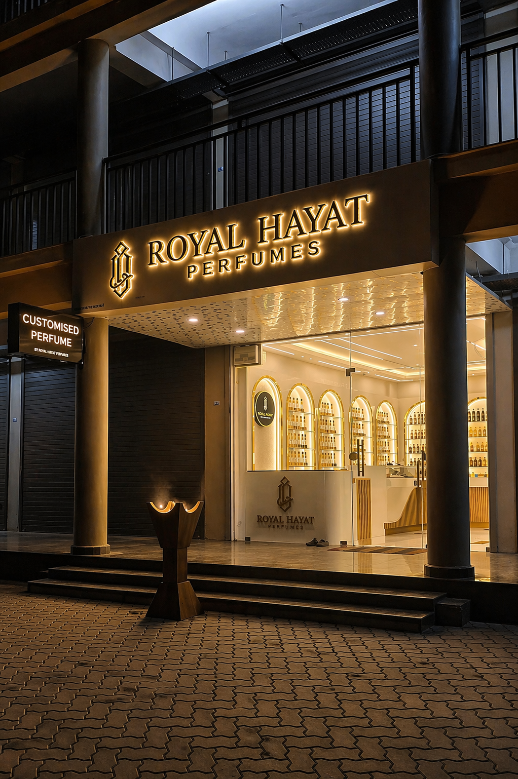 Royal Hayat Perfumes storefront in Thodupuzha at night, with the golden sign glowing above the entrance
